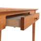 American Shaker Writing Desk, a beautifully crafted wooden table with a partially open drawer, featuring a smooth finish and minimalist design from sustainably harvested hardwood by Vermont artisans.
