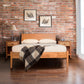 Andover Modern Incline Bed by Maple Corner Woodworks crafted from solid wood with white bedding and a plaid blanket, highlighting its sleek mid-century modern design.