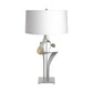 Antasia #2 Table Lamp by Hubbardton Forge with a sculptural metallic base and white drum shade, showcasing modern artisan craftsmanship.