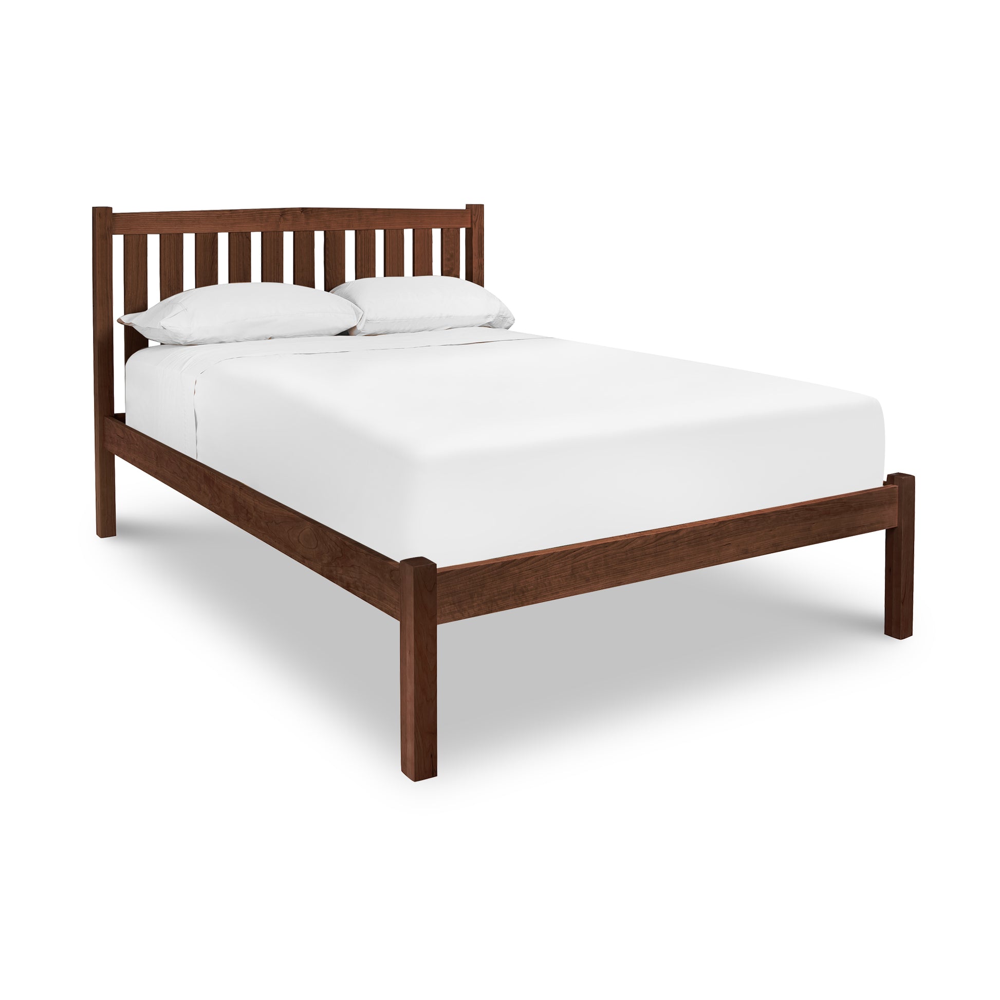 Bennington Bed in walnut with slatted headboard and white bedding by Vermont Furniture Designs, viewed from an elevated angle.