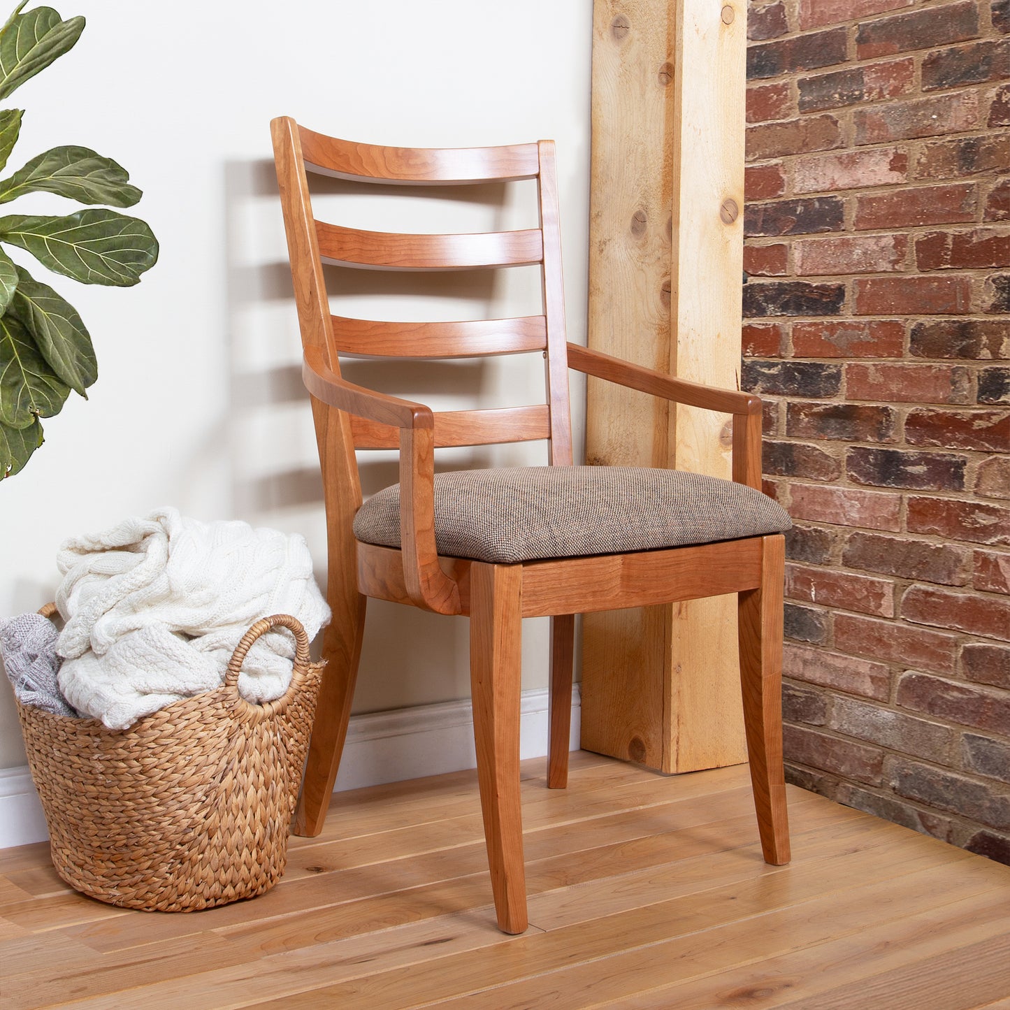 The Bromley Ladder-Back Chair by Vermont Woods Studios features black upholstery, showcasing fine American craftsmanship and modern design.