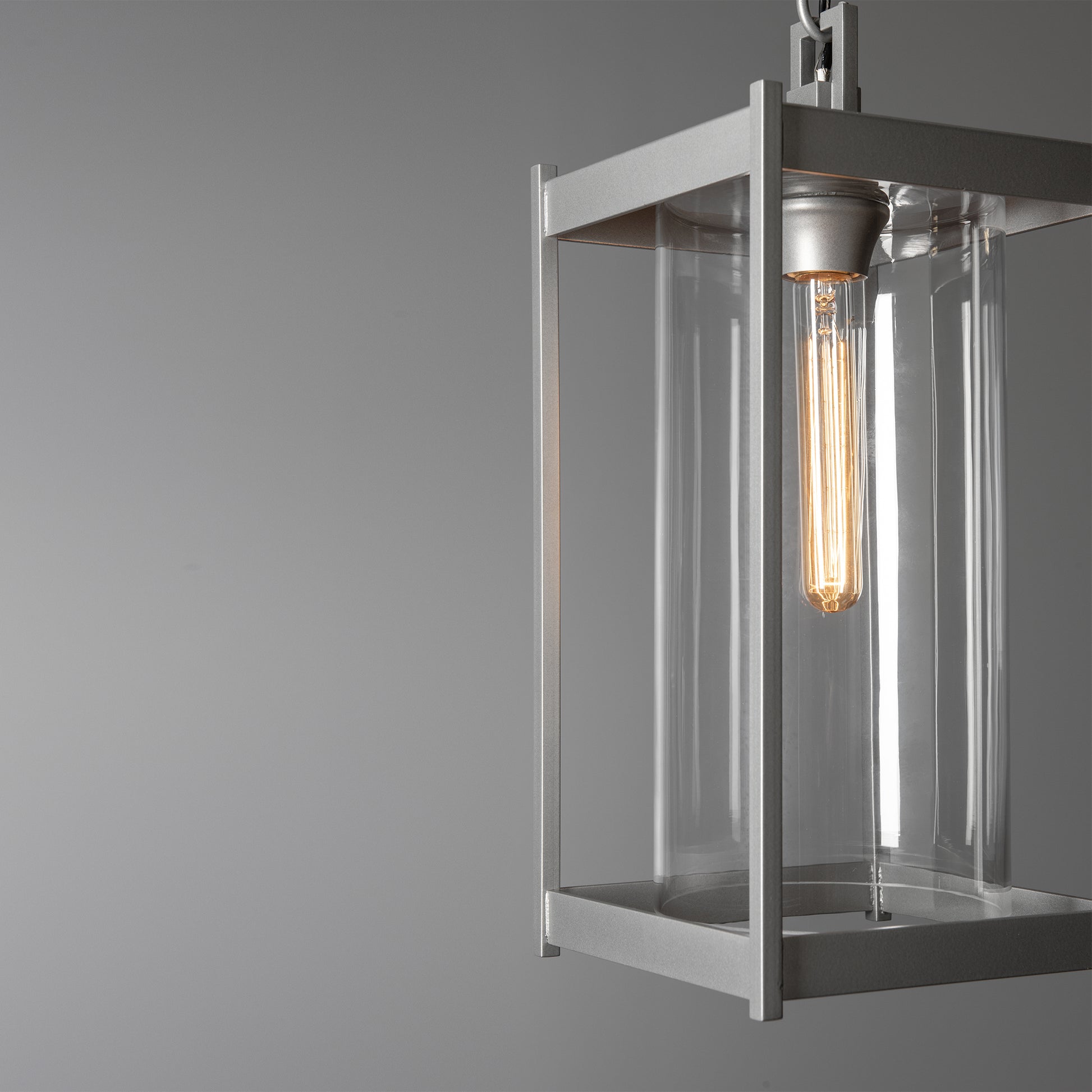 Cela Large Outdoor Lantern by Hubbardton Forge with clear glass body and glowing bulb, showcasing modern craftsmanship and elegant outdoor design.