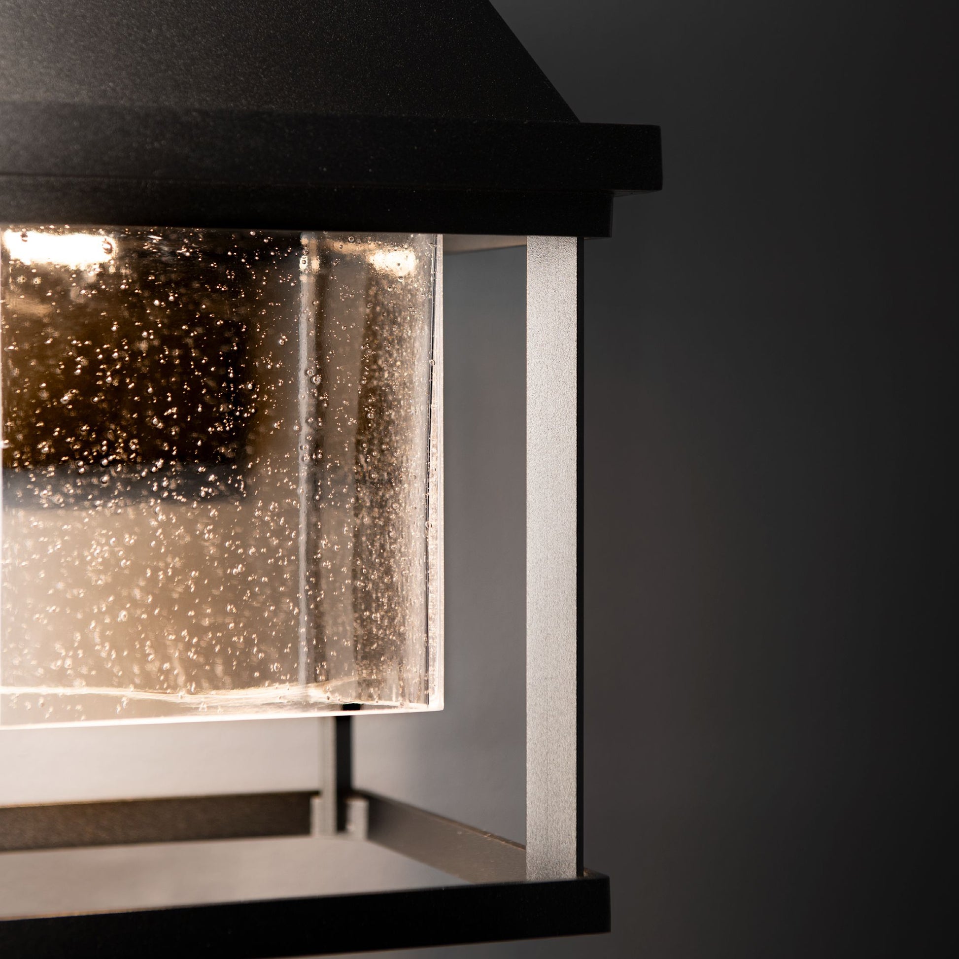 Hubbardton Forge Dorset Small Dark Sky Friendly Outdoor Sconce featuring a black metal frame and glass with water droplets, highlighting its handcrafted design.