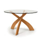 Copeland Furniture Entwine Round Dining Table with intersecting cherry wood legs and a clear glass top.