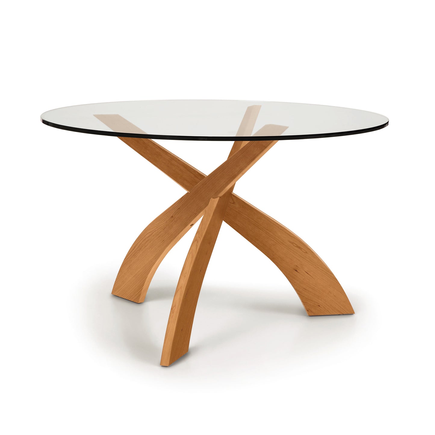 Copeland Furniture Entwine Round Dining Table with intersecting cherry wood legs and a clear glass top.