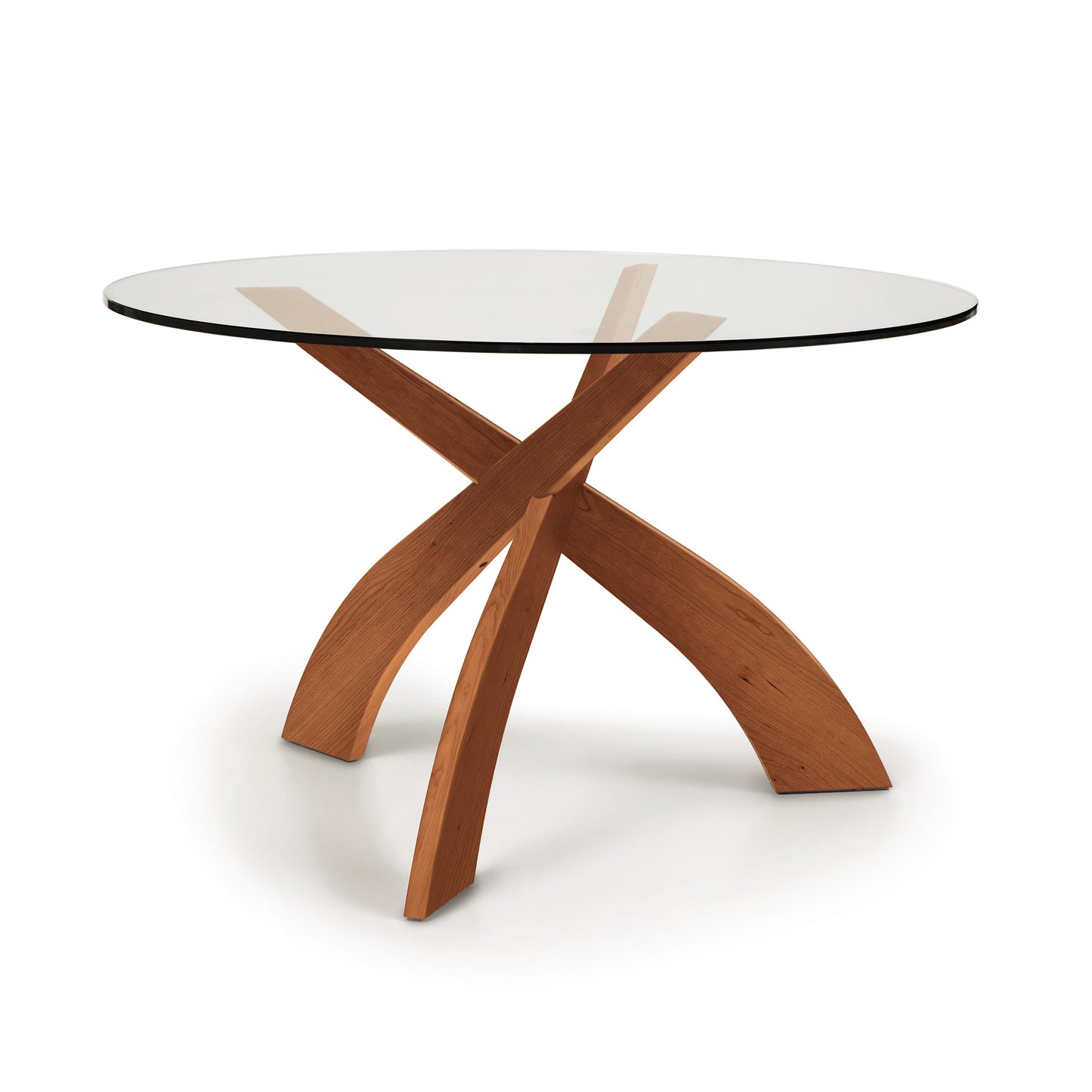 Entwine Round Glass Top Dining Table by Copeland Furniture with sculptural intersecting cherry wood legs and a clear tempered glass top.
