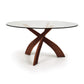 Copeland Entwine Round Dining Table with tempered glass top and three sculptural cherry wood legs, showcasing modern craftsmanship.