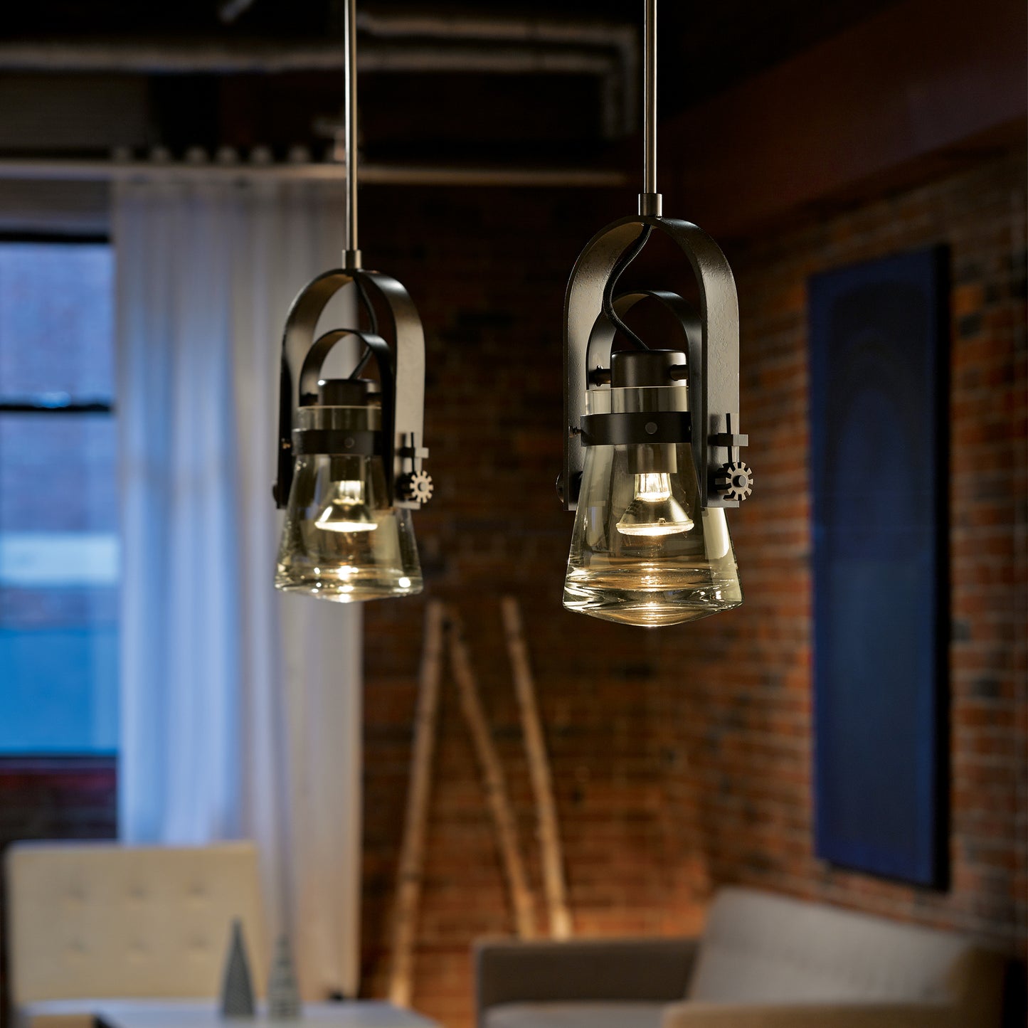 Pair of Hubbardton Forge Erlenmeyer Large Mini Pendants with clear glass shades suspended above, showcasing their artisan-crafted design.