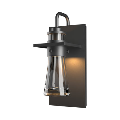 Close-up of the Hubbardton Forge Erlenmeyer Medium Outdoor Sconce with black metal base and clear glass, showcasing American-made craftsmanship.