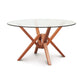 Copeland Furniture Exeter round glass top table featuring a striking geometric hardwood base, highlighted against a plain white background.