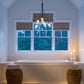 Hubbardton Forge Flora 6-Arm Chandelier hanging over a white bathtub with lit candles on the edge, complemented by elegant wicker side tables.