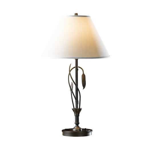 Handcrafted Hubbardton Forge table lamp featuring a white conical shade and artistic bronze base with forged leaf and vase design, American made.