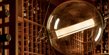 A large wine bottle hanging from a ceiling in a wine cellar.