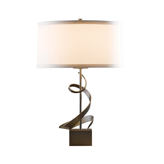 Hubbardton Forge Spiral Table Lamp featuring a white cylindrical shade and elegant bronze swirl on a sturdy square stand.
