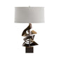 Hubbardton Forge Gallery Two Fold Table Lamp with a sculptural bronze metal base and white drum shade, showcasing expert American craftsmanship.
