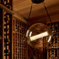 Hubbardton Forge Otto Sphere Pendant casting light on elegant wooden wine racks.