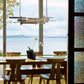 American-made dining table with four chairs, crafted from fine wood, beneath a modern Hubbardton Forge LED pendant. High-quality craftsmanship featured.