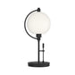 Pluto Table Lamp by Hubbardton Forge with a round white glass shade and sleek black metal frame, showcasing minimalist modern design.