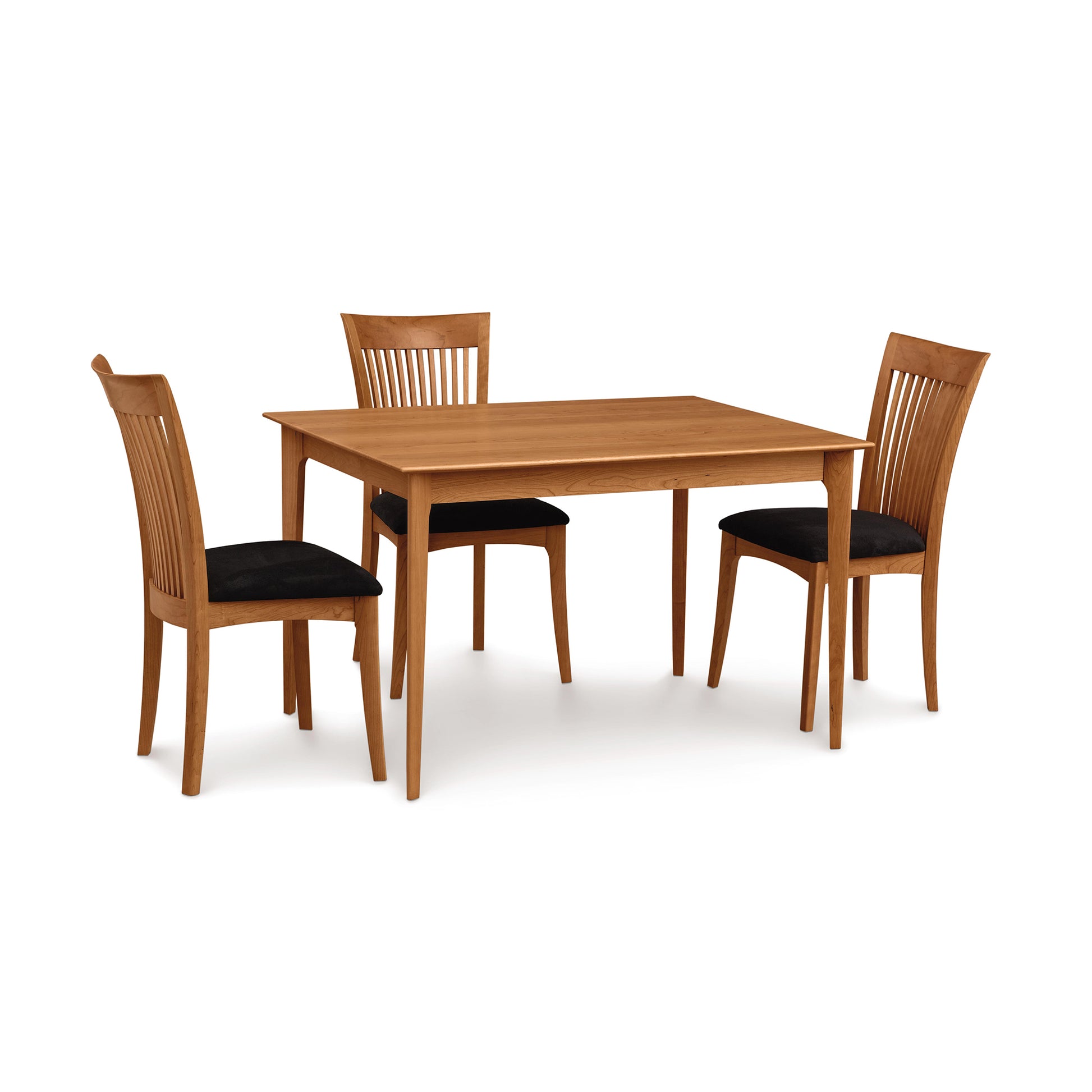 Sarah Shaker solid-top table with tapered legs, paired with three matching dining chairs featuring black cushioned seats by Copeland Furniture.