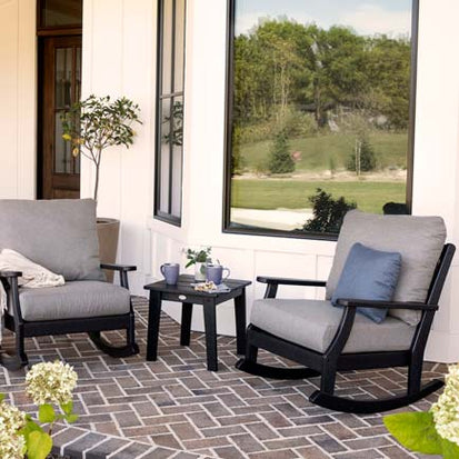 A patio with two rocking chairs and a table.
