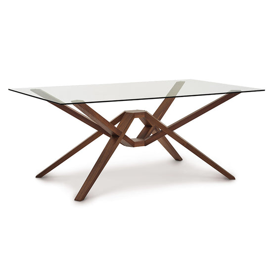 A modern dining table with a glass top and wooden legs.