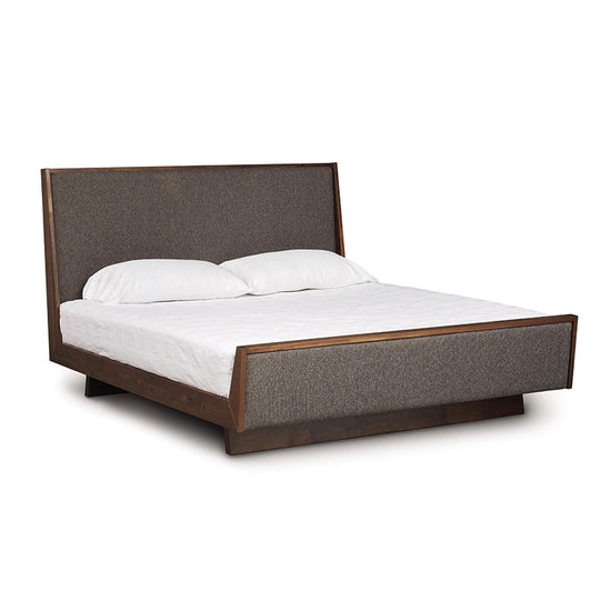 A bed with a wooden frame and upholstered headboard.