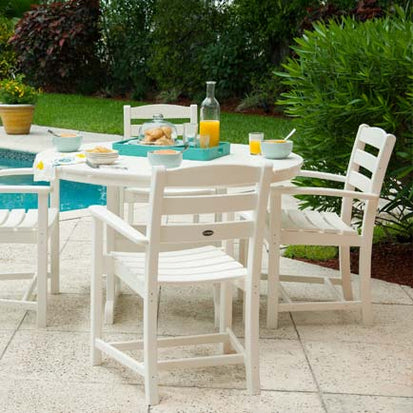 A white dining table and chairs near a pool.