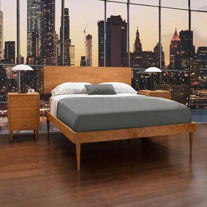 A bed in a bedroom with a mural of a city.
