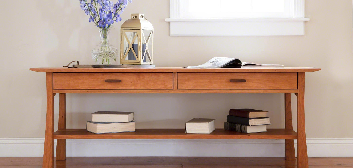 A wooden console table with books and flowers on it.