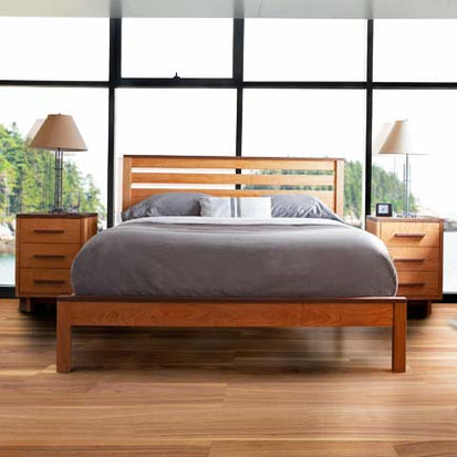 A bed in a bedroom with hardwood floors and large windows.