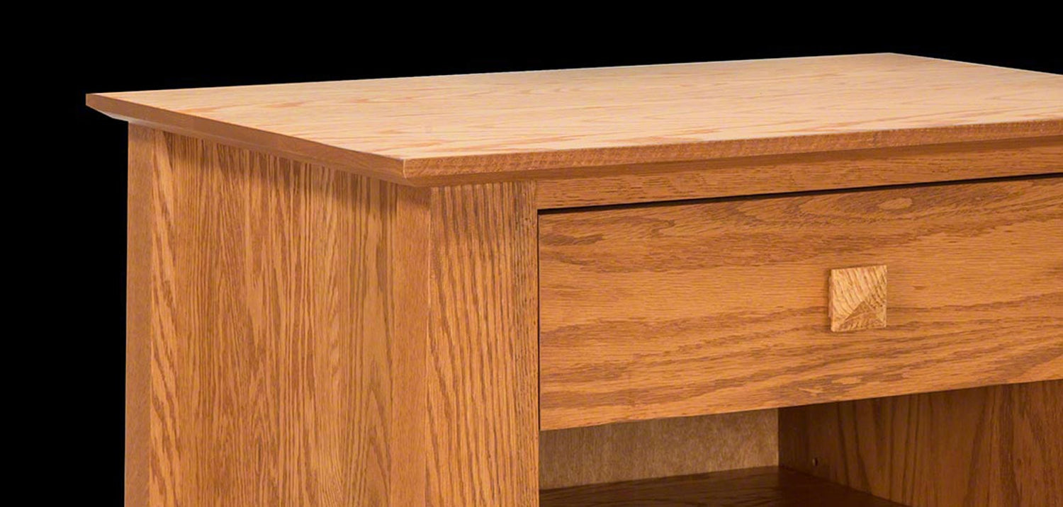 A wooden piece of furniture with a smooth surface. The top part appears to be a flat tabletop, and below it is a drawer with a square knob. The lower section shows an open storage space. The wood has a natural, light brown finish.