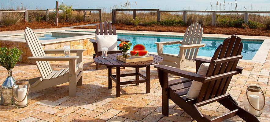 A table and chairs on a brick patio next to a pool.