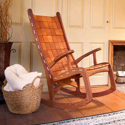 A rocking chair in front of a fireplace.