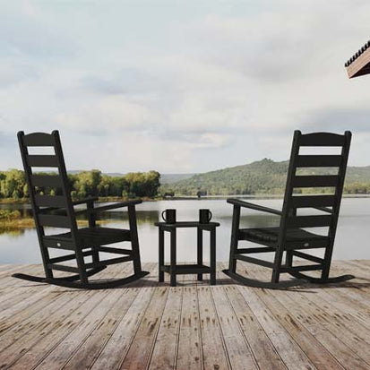 Two black rocking chairs on a dock overlooking a lake.